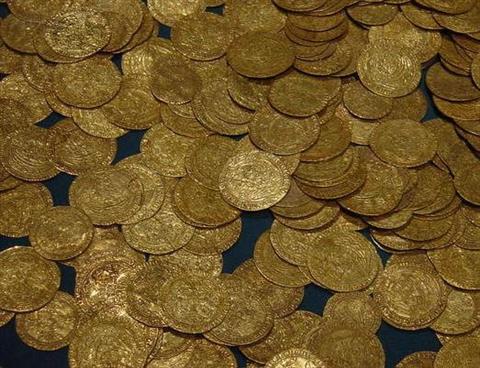 Numerous ancient gold coilns, strewn on a black background